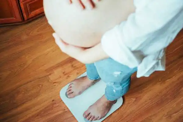 Image of woman weighing herself and experiencing weight gain through pregnancy Brierley Hill